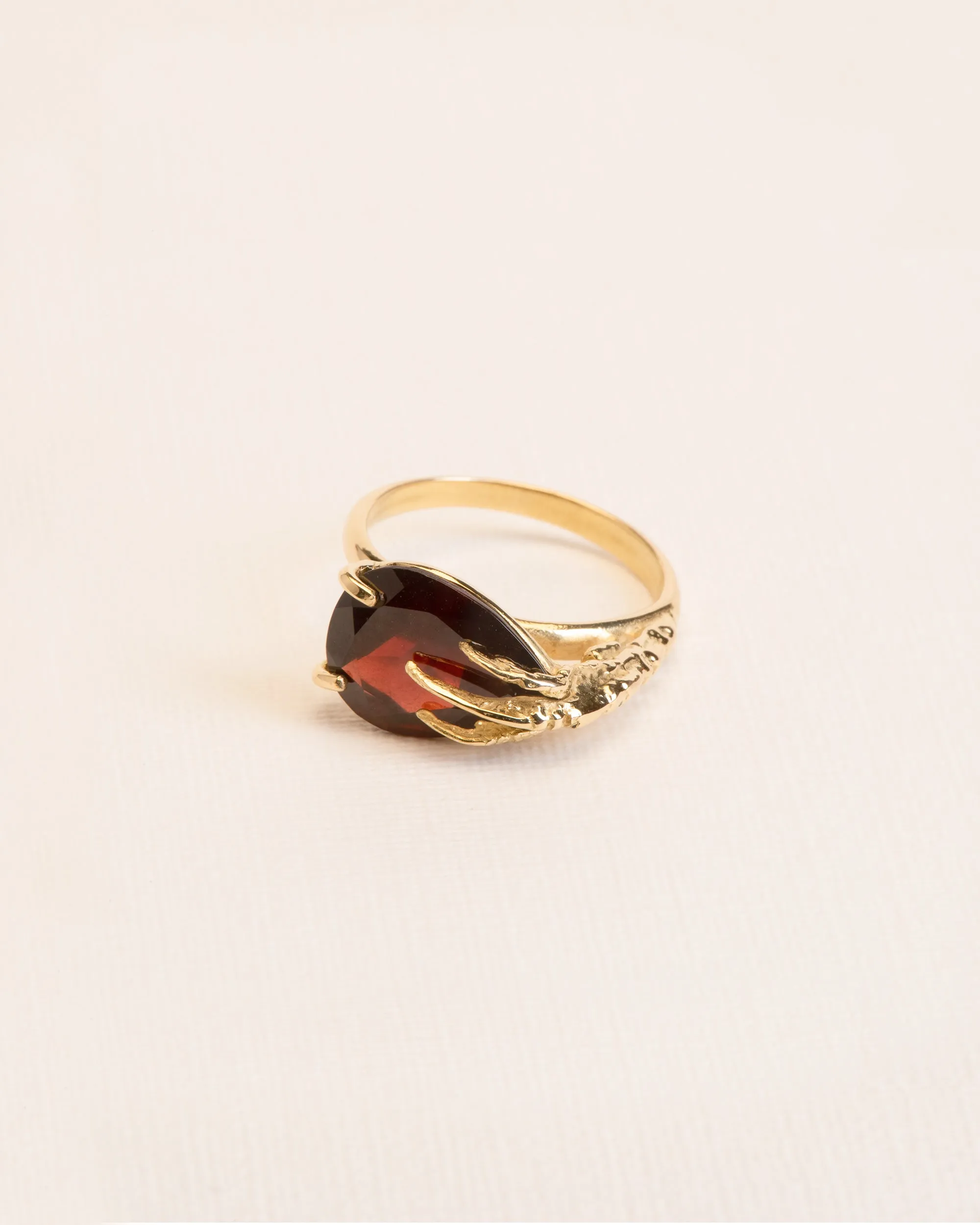 Signature grigri ring clasping a garnet in 18 ct. gold